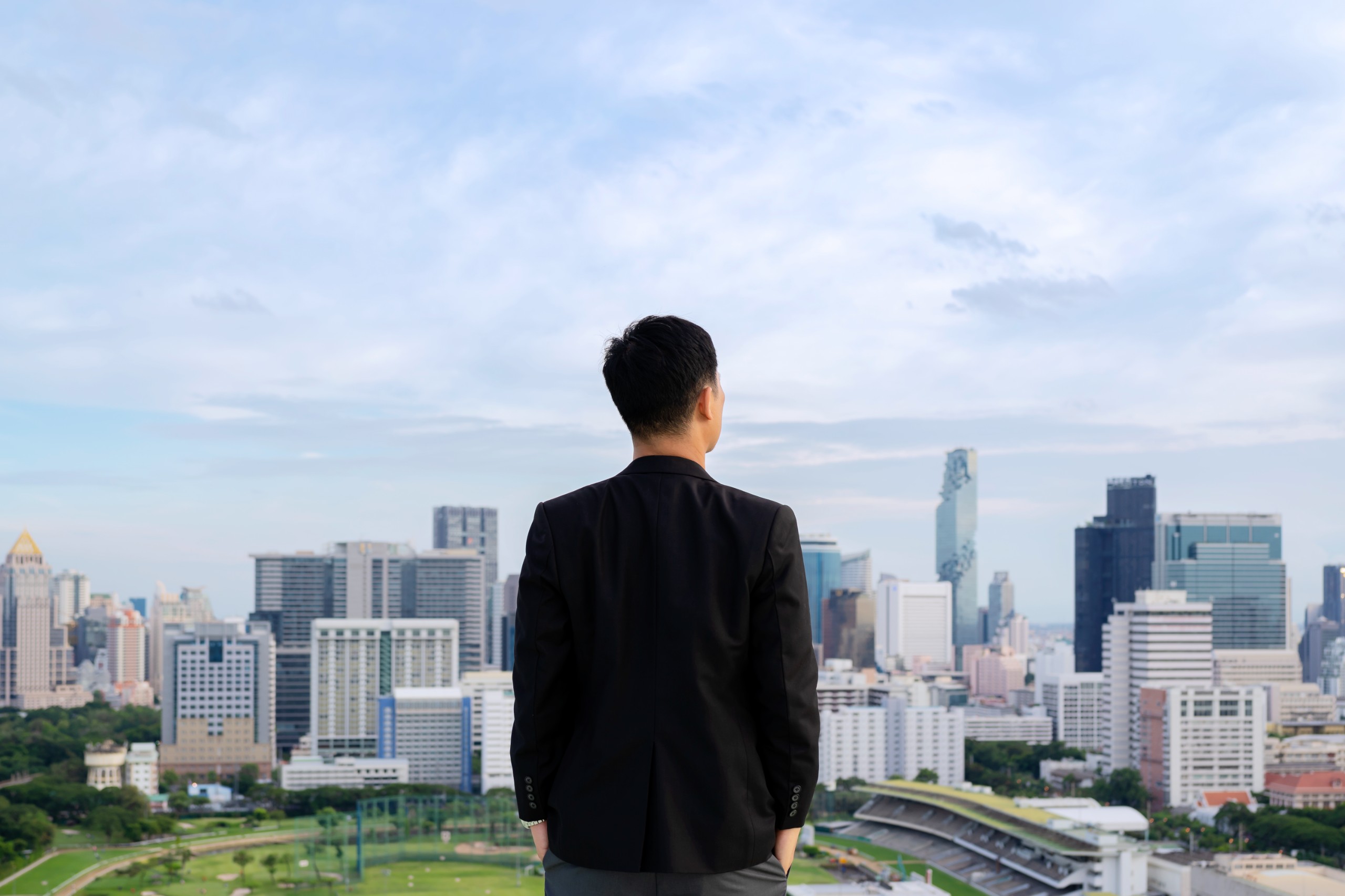 directors fit side-view-thoughtful-young-businessman-standing-concrete-rooftop-skyscraper-watching-big-city-sunset-business-research-concept